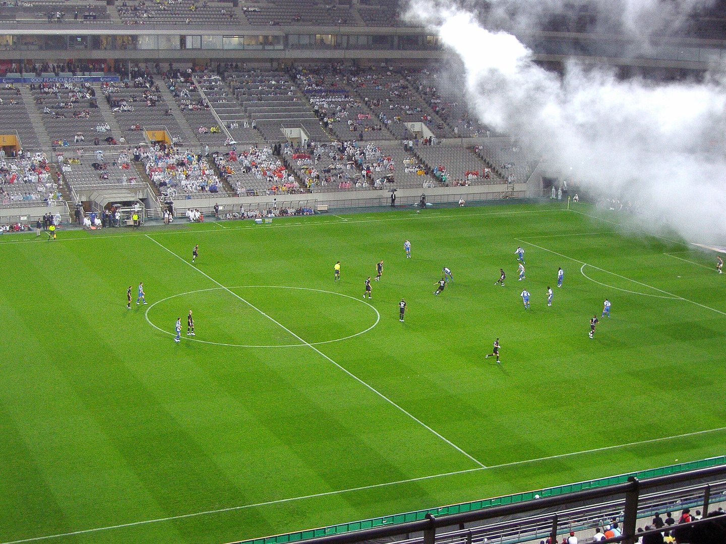 Players kicking off a football match in a large Korean stadium