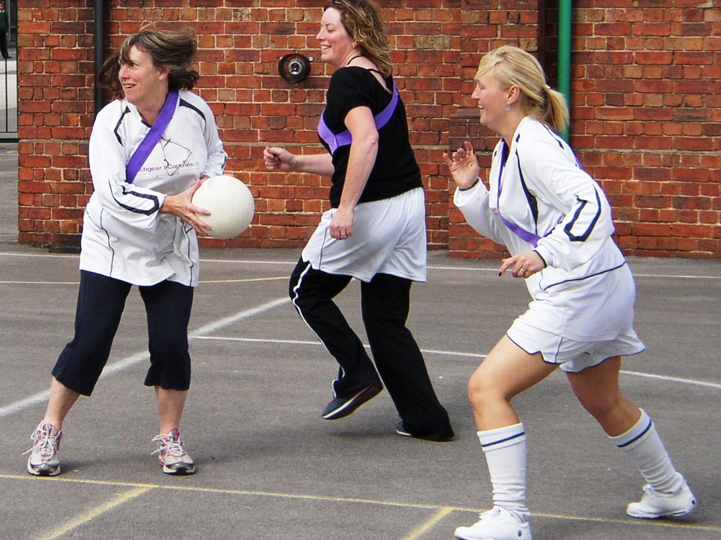 Netball players competing for a high ball during an outdoor match