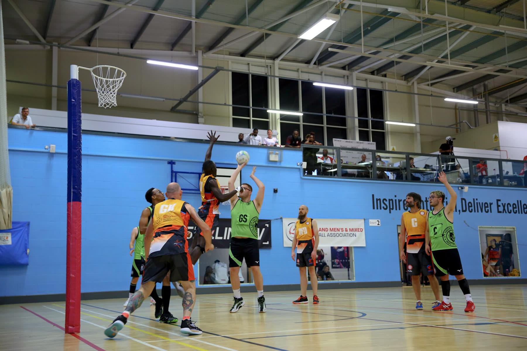 Netball players contesting a pass during an indoor match
